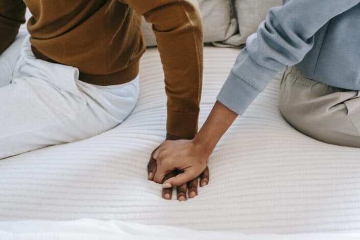 mujer tocando la mano de su hombre en la cama