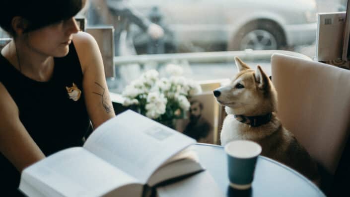 Mujer sentada en el café con su perro a su lado