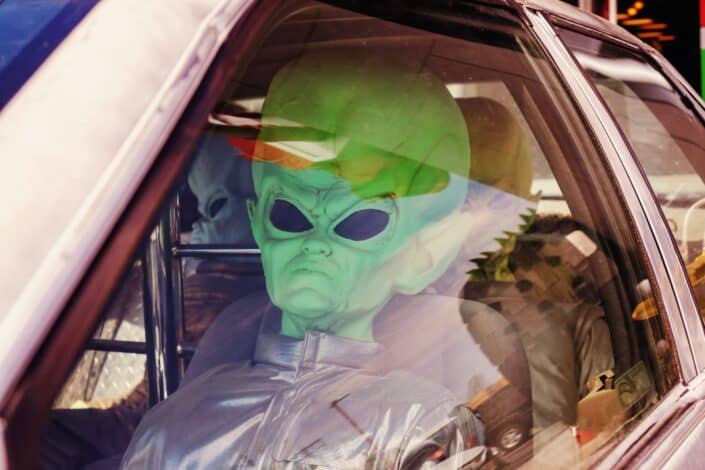 Grupo de amigos vistiendo traje alienígena sentado en un coche