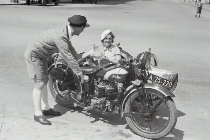 Foto de época de un hombre y una mujer montando una vieja moto