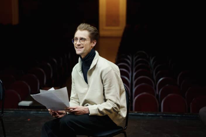 Hombre con gafas sosteniendo su guión para un espectáculo de teatro