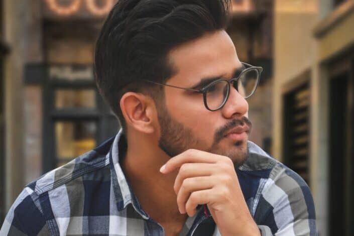 Hombre con gafas vistiendo una camisa a cuadros en pensamiento profundo