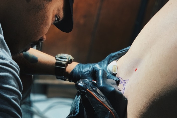 hombre poniendo un tatuaje en la espalda de un cliente