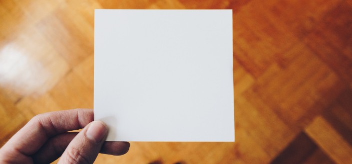 mano sosteniendo una hoja blanca de papel en blanco