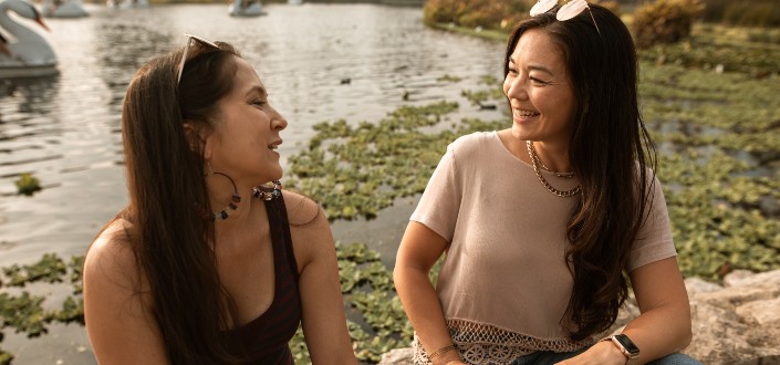 Dos señoras que tienen conversaciones amistosas cerca del lago.