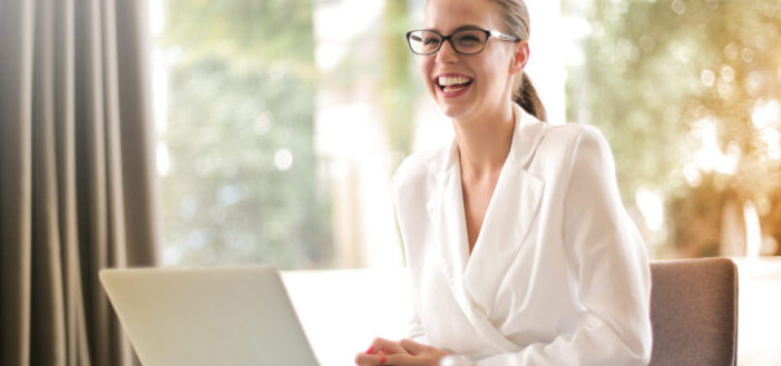 Mujer de negocios riéndose y trabajando en la oficina con una laptop