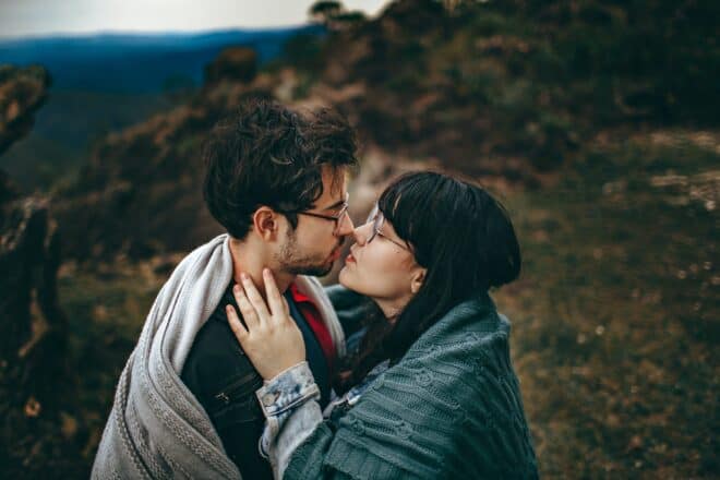 cómo besar a un chico - Pareja compartiendo un beso en una colina